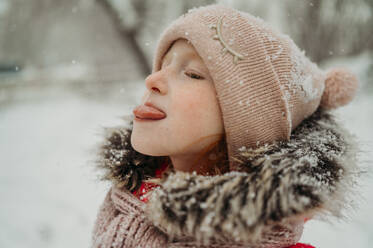 Girl catching snow with tongue in winter - ANAF02599