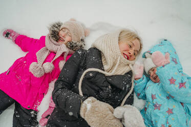 Happy woman enjoying with daughters on snow - ANAF02601