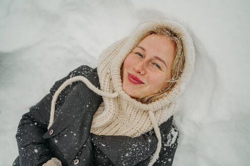 Happy young woman lying on snow - ANAF02603