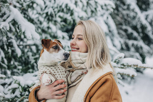 Happy woman with blond hair holding dog in arms - VSNF01494