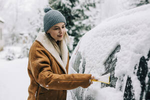 Woman clearing snow from car with scraper - VSNF01498