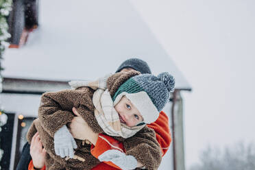 Smiling boy in arms of father on snowy day - VSNF01503