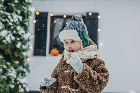 Boy eating icicle on snowy day - VSNF01506