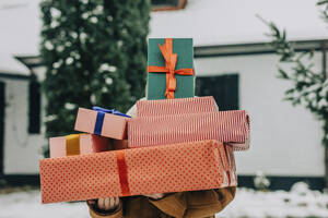 Frau bedeckt Gesicht mit Weihnachtsgeschenken im Winter - VSNF01518