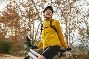 Smiling woman with mountain bike near trees in forest - EBSF04322