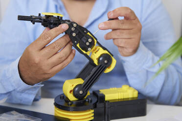 Engineer working on robotic arm in office - AZF00589