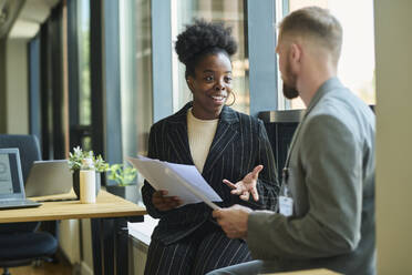 Businessman and businesswoman having discussion over documents in office - DSHF01466