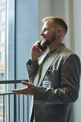 Geschäftsmann, der im Büro mit seinem Smartphone telefoniert - DSHF01482