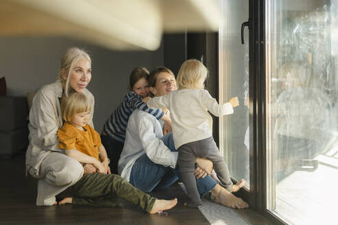 Happy family having fun sitting near glass door at home - SEAF02079