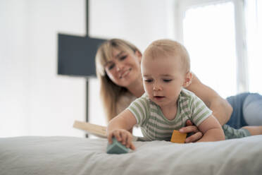 Son playing blocks with mother on bed at home - JOSEF22395