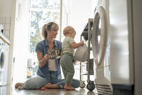 Mother and son arranging utensils in kitchen trolley at home - JOSEF22396