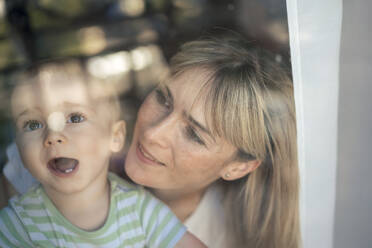 Cute boy with mother behind transparent glass window - JOSEF22404