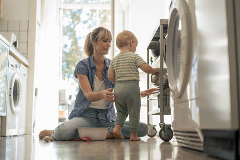 Mother and son arranging bowls in kitchen trolley at home - JOSEF22414