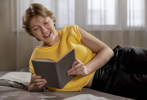 Glückliche Frau liest zu Hause ein Buch - MBLF00182