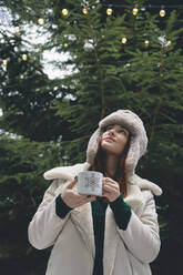 Junge Frau mit Jägermütze hält Kaffeetasse in der Hand - OLRF00001