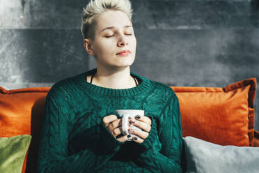 Woman with short hair holding coffee mug at home - OLRF00007