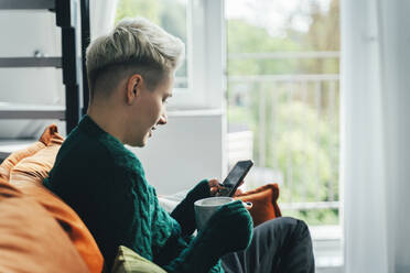 Young woman using smart phone and sitting at home - OLRF00008