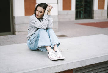 Young woman sitting on concrete bench - SVCF00450