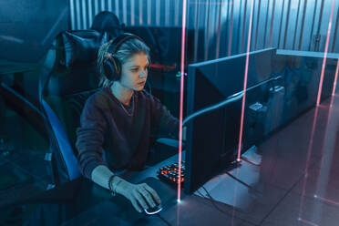 Junger Gamer, der Kopfhörer trägt und Spiele am Computer spielt - EVKF00091