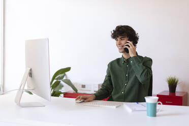 Lächelnder Geschäftsmann beim Multitasking im Heimbüro - LMCF00725