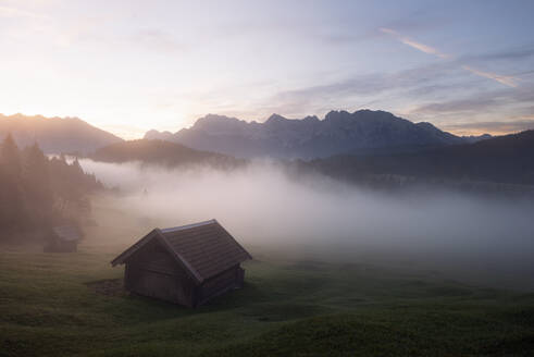 Germany, Bavaria, Alpine hut at foggy sunrise - RUEF04263