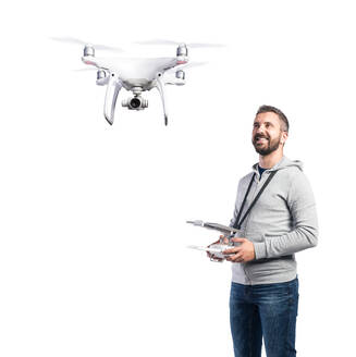 Mann mit Fernsteuerung und fliegender Drohne mit Kamera, Studioaufnahme auf weißem Hintergrund, isoliert. - HPIF35958
