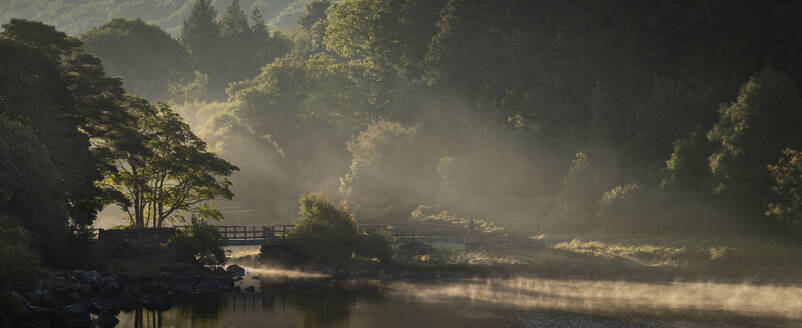 Fußgängerbrücke über Nant Gwyd und Llynnau Mymbyr bei Sonnenaufgang mit Morgennebel, Capel Curig, Snowdonia National Park, Wales, Vereinigtes Königreich, Europa - RHPLF30177