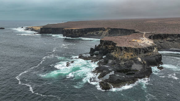 Aerial of the wild coastline with basalt pools on the Atlantic coastline, Dombe Grande, Namibre, Angola, Africa - RHPLF30440