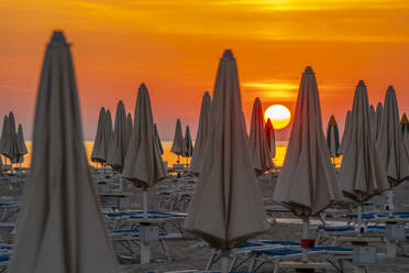 Blick auf Sonnenaufgang und Sonnenschirme am Lido am Strand von Rimini, Rimini, Emilia-Romagna, Italien, Europa - RHPLF31317