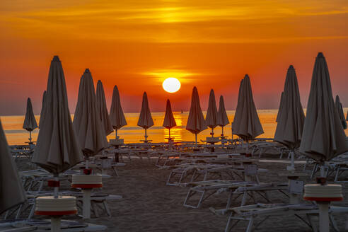 Blick auf Sonnenaufgang und Sonnenschirme am Lido am Strand von Rimini, Rimini, Emilia-Romagna, Italien, Europa - RHPLF31318