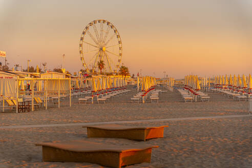 Blick auf Riesenrad und Sonnenschirme auf dem Lido am Strand von Rimini bei Sonnenaufgang, Rimini, Emilia-Romagna, Italien, Europa - RHPLF31323