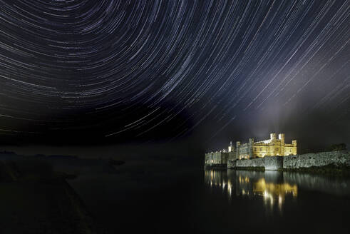 Beleuchtetes Schloss Leeds, das sich im Wassergraben spiegelt und Sternenspuren am Nachthimmel zeigt, in der Nähe von Maidstone, Kent, England, Vereinigtes Königreich, Europa - RHPLF31458