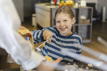 Glückliches Mädchen mit Mutter beim Schneiden von Teig in der Nudelmaschine - SEAF02116