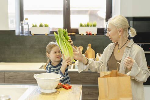 Mädchen gibt Großmutter in der Küche zu Hause Salat - SEAF02126