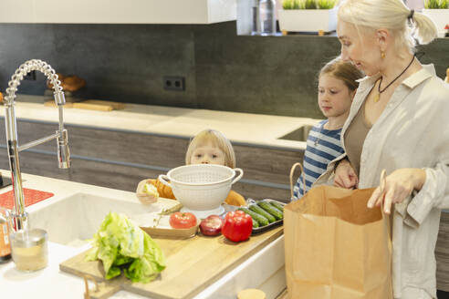 Großmutter mit Enkelin und Enkel bei der Zubereitung von Essen zu Hause - SEAF02128
