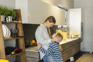 Liebevolle Mutter umarmt Tochter in der Küche zu Hause - SEAF02138