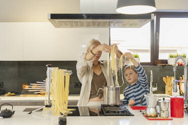 Großmutter und Enkelin kochen zu Hause Spaghetti in einem Kochtopf - SEAF02142