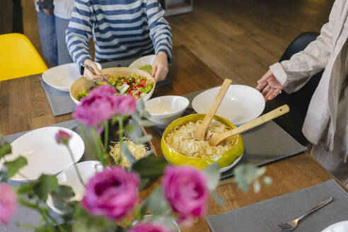 Mädchen serviert Essen mit Großmutter am Esstisch zu Hause - SEAF02146