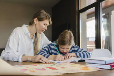 Mutter hilft Tochter bei den Hausaufgaben am Schreibtisch - SEAF02159