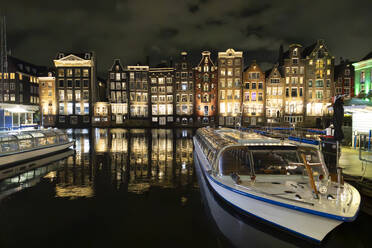 Tourboats in front of buildings in Amsterdam city at night - JCCMF10990