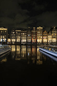 Beleuchtete Gebäude in der Nähe des Flusses bei Nacht in der Stadt Amsterdam - JCCMF10991