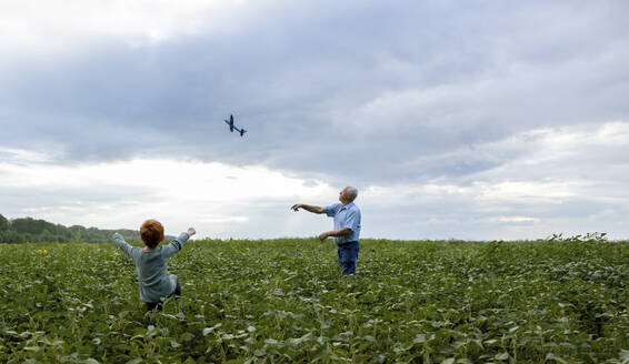 Großvater und Enkel fliegen Spielzeugflugzeug im Feld - MBLF00201