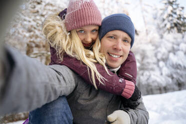 Smiling mature man taking selfie with daughter in snow forest - NJAF00720