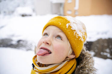 Junge, der im Winter mit der Zunge Schnee auffängt - NJAF00728