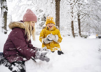 Glückliche Geschwister spielen im Schnee - NJAF00729