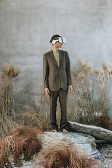 Geschäftsmann steht auf einem Felsen und trägt einen Virtual-Reality-Simulator im Garten - YTF01509