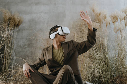 Businessman using virtual reality simulator and gesturing in garden - YTF01519