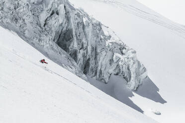 Seitenansicht eines nicht erkennbaren Skifahrers, der auf einem schneebedeckten Berg Ski fährt, während er seinen Winterurlaub in den Schweizer Alpen an einem sonnigen Tag genießt - ADSF50574