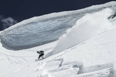 Ganzer Körper eines nicht erkennbaren Skifahrers, der auf einem schneebedeckten Berg Ski fährt, während er seinen Winterurlaub in den Schweizer Alpen an einem sonnigen Tag genießt - ADSF50575