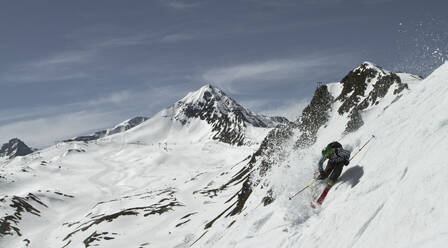 Unbekannter Skifahrer reitet auf Skiern auf einem schneebedeckten Berg, während er seinen Winterurlaub in den Schweizer Alpen an einem sonnigen Tag genießt - ADSF50594